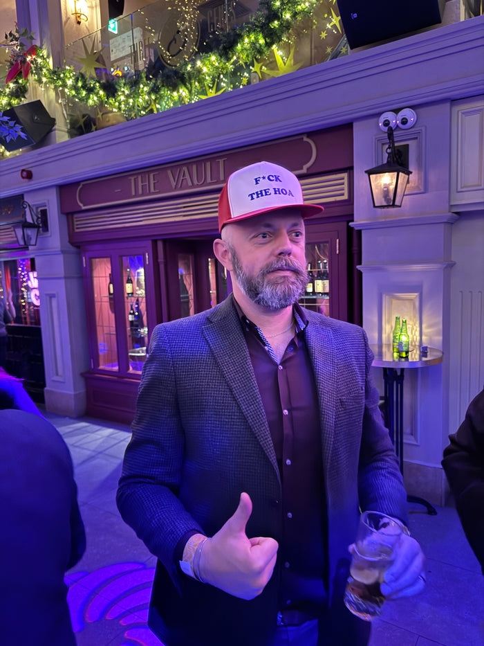 Customer in a blazer wearing the red hat at a festive venue