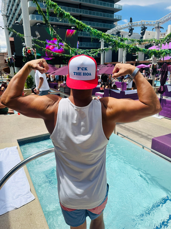 Customer flexing by the pool while wearing a red F*ck the HOA hat backward