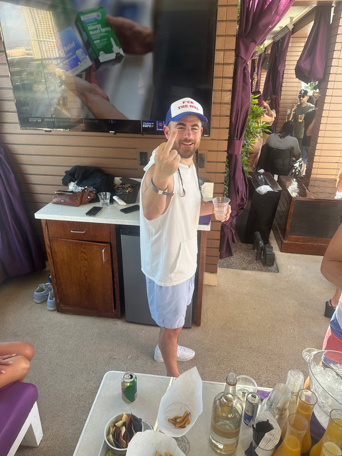 Customer wearing a blue F*ck the HOA hat and making a cheeky gesture at a gathering