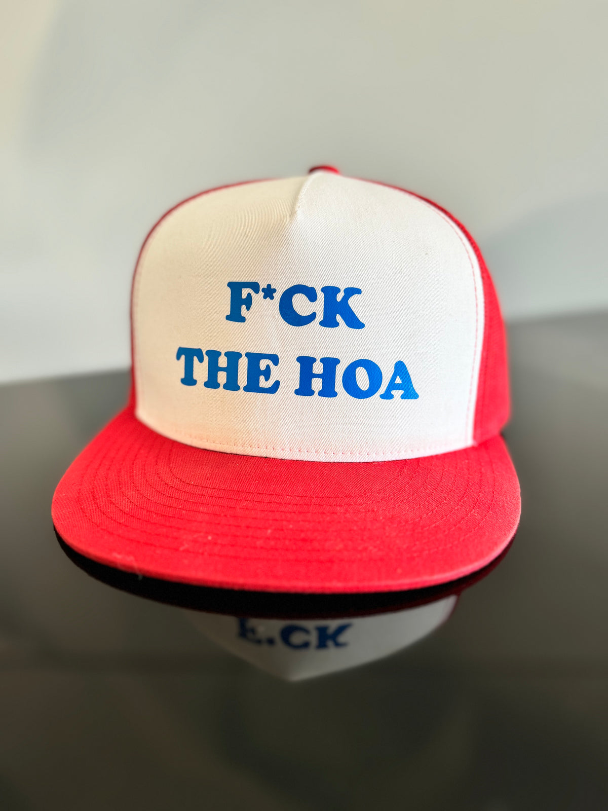 Original red and white Fck The HOA trucker hat with blue lettering